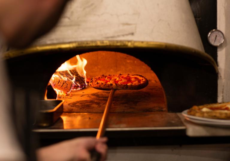 Pizza going into a pizza oven.