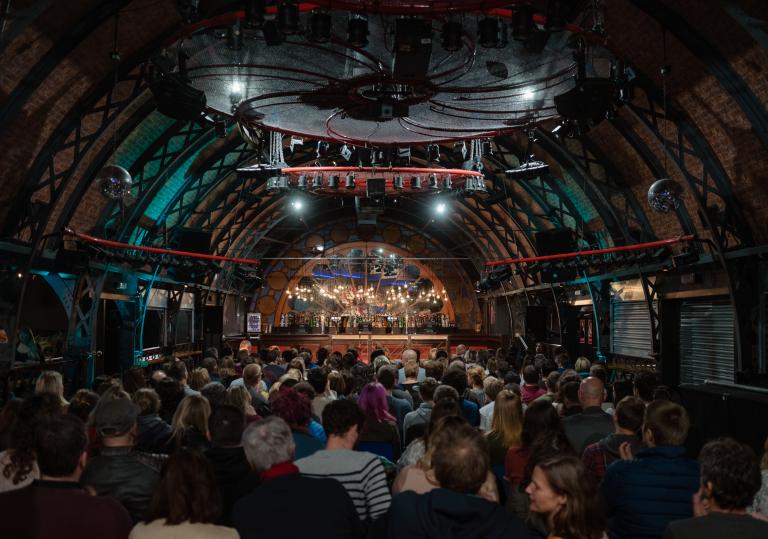 Inside a large venue where people are watching a comedy show
