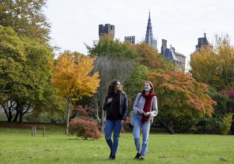 Two women walking in an autumnal park.