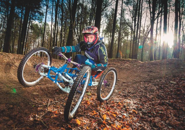 A man in a disability bike on a downhill forest biking course