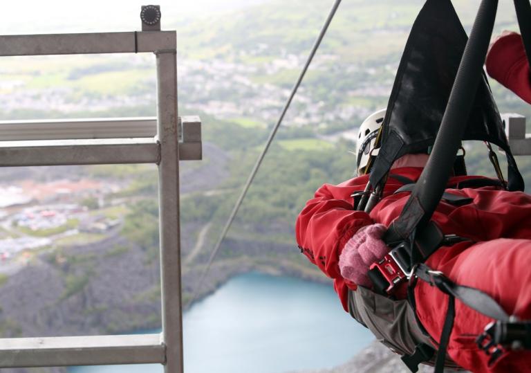 a man strapped into a zipwire overlooking a large quarry