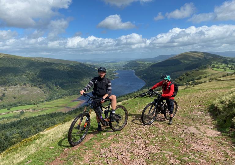 Two people on mountain bikes overlooking a lake.