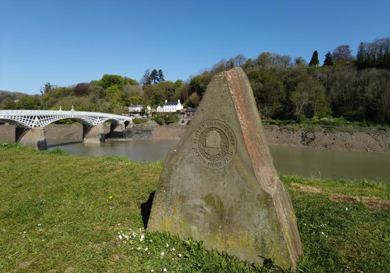 A stone waymarker by a river.