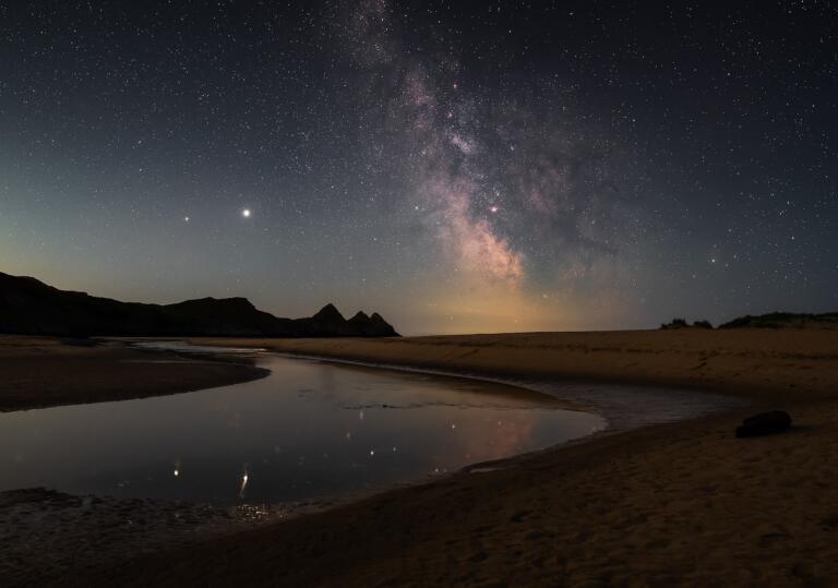The Milky Way in the night sky highlighting the beach at Three Cliffs Bay, Gower