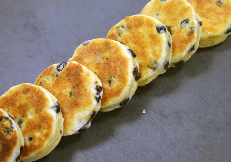 A row of welsh cakes lying on a slate grey surface. 