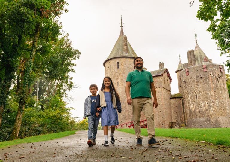 Father and two children walking in front of a fairytale castle  