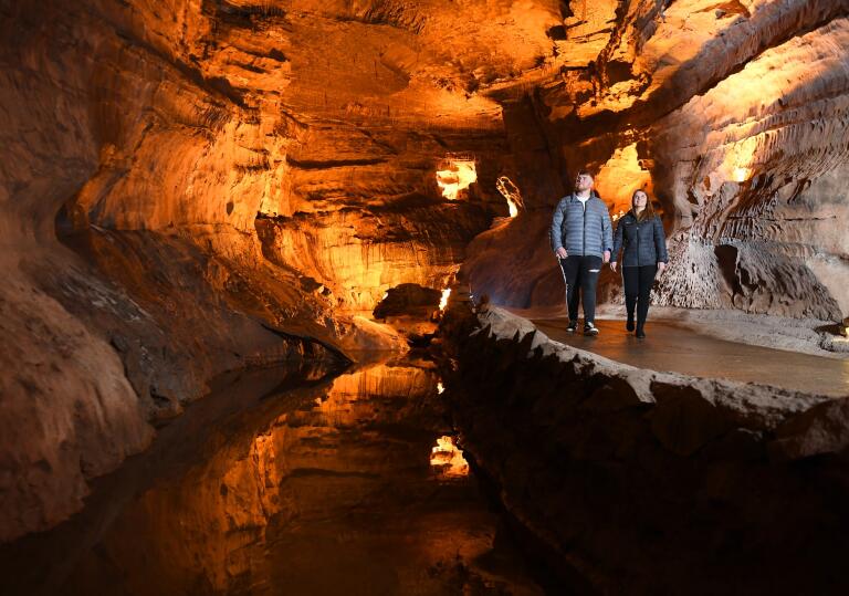 Two people walking along an underground path in a cave.