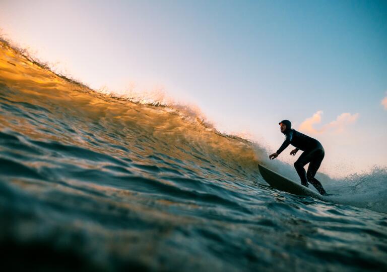 man on a surfboard riding a wave at dusk.