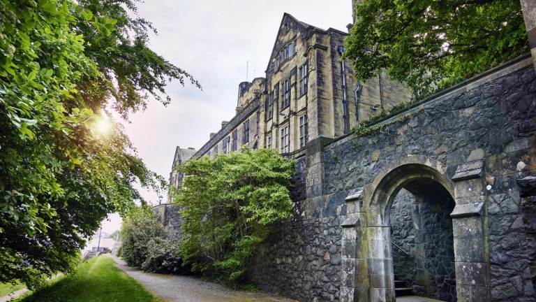 An external view of a university alongside a path lined with greenery.