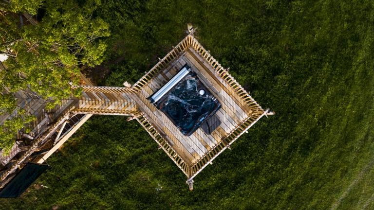 Drone shot of a hot tub on a treehouse platform.