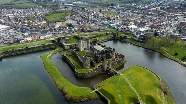 Aerial shot of Caerphilly Castle surrounded by the moat and green banks.