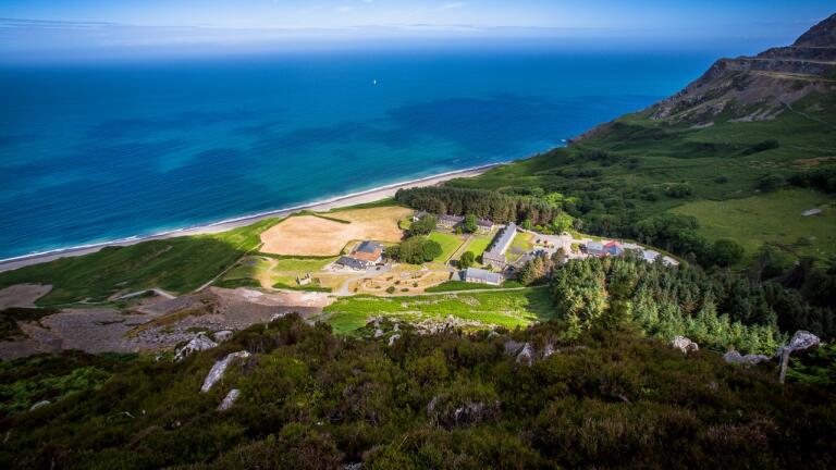 Aerial shot of a Welsh language cultural centre surrounded by sea and mountains.