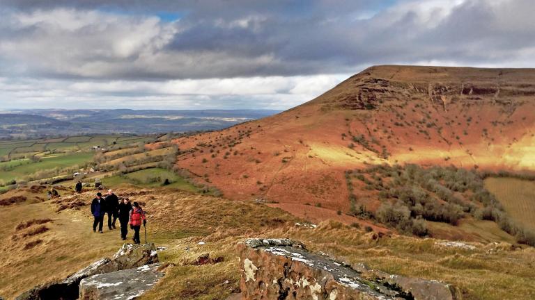 Four popel walking across a rocky hillside during Crickhowell Walking Festival, Powys
