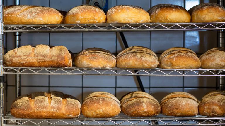 Three metal shelves of freshly baked loaves of bread.