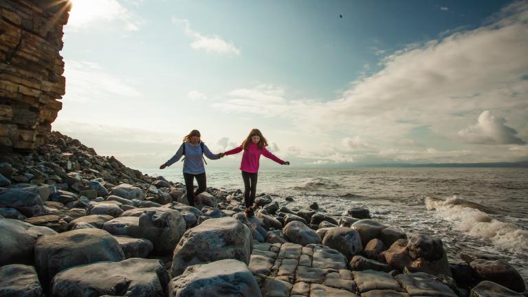 Two young people on the rocky seashore near Llantwit Major.