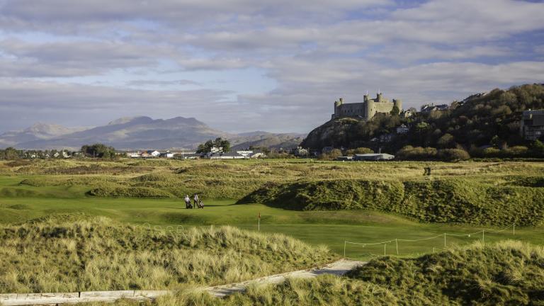 Golfers on Royal St. David's Golf course with castle and mountains in the background.