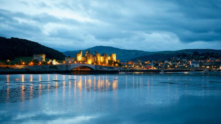 Conwy Castle and the town of Conwy lit up at dusk.