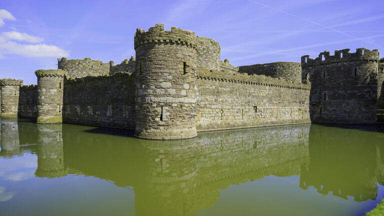 Panoramic view of the south west corner of Beaumaris Castle surrounded by water.