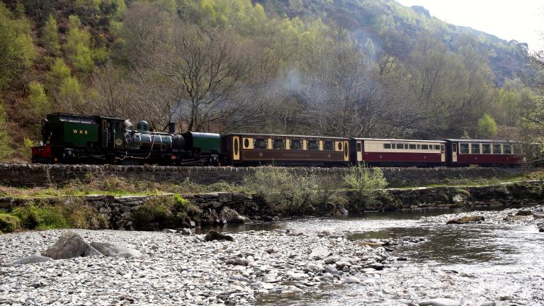 A train running alongside a river.