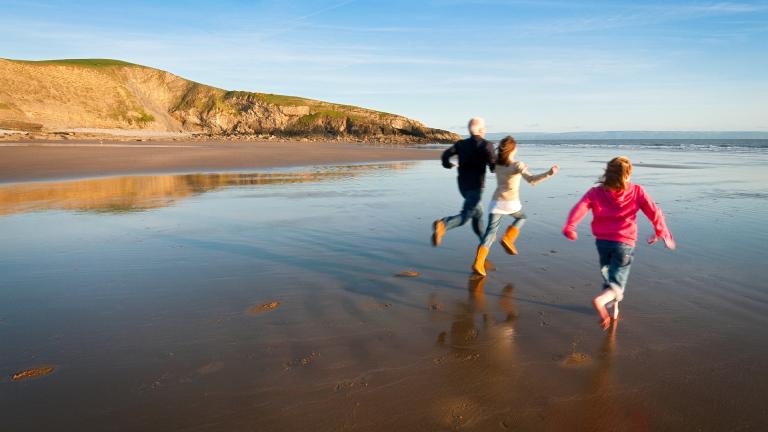 Image of a family running on the beach.