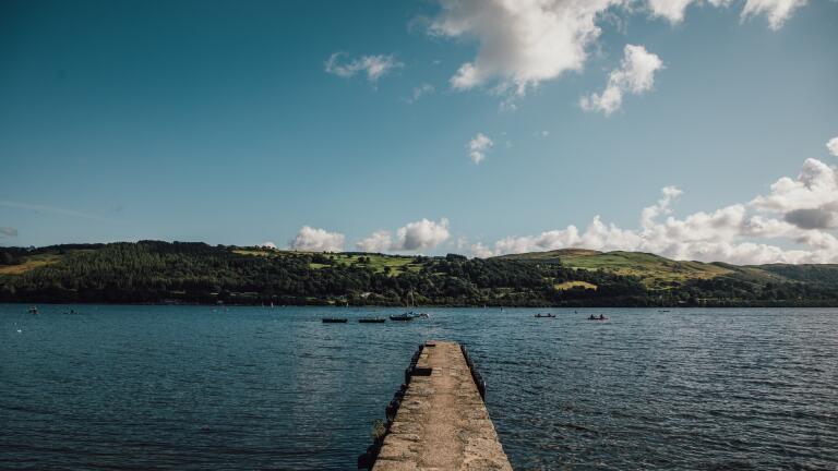 A jetty out into a lake with hills in the background.