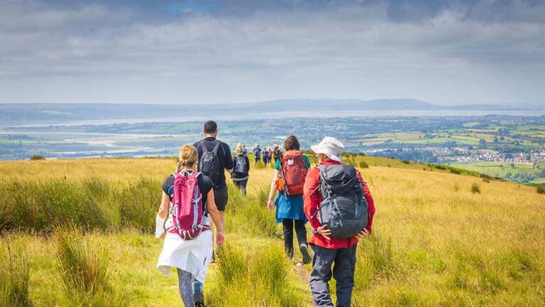 A group of walkers on a hill looking down over an estuary.