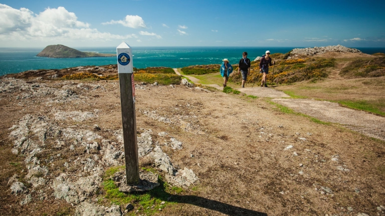 Walkers on Mynydd Mawr with the sea in the background.