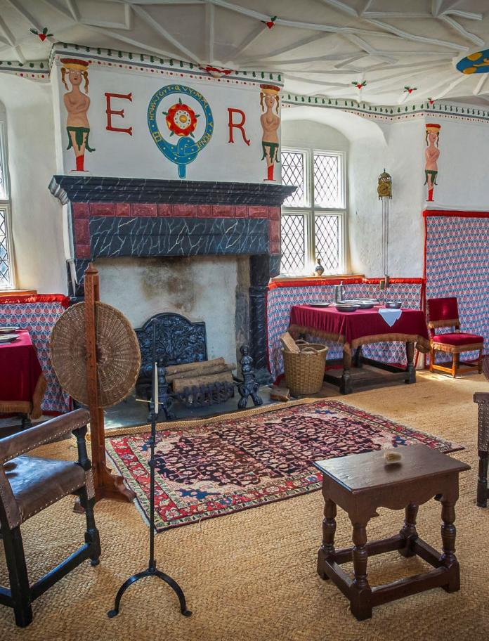 One of the rooms with an ornate fireplace, decor and wooden chairs at Plas Mawr, Conwy.