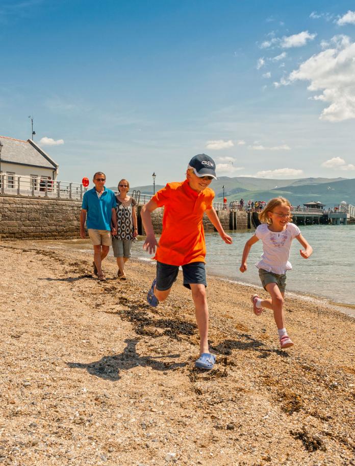Family on beach at Beaumaris with pier in background.