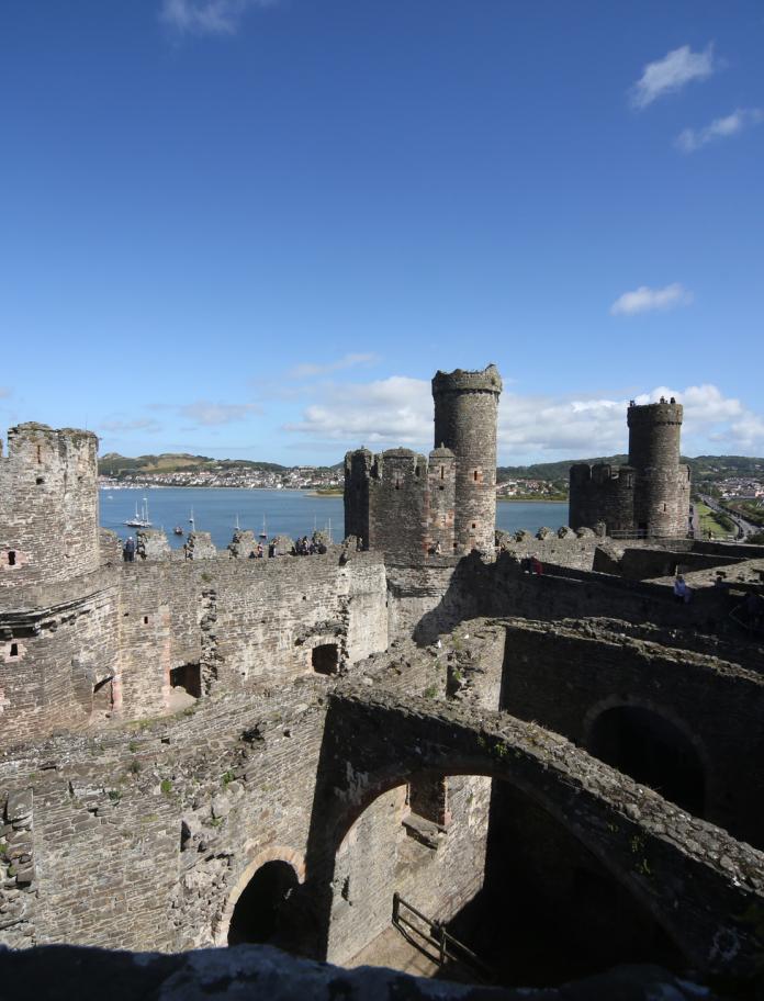 View of the top of the towers of Conwy Castle and the sea in the background.