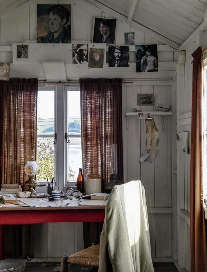 In Dylan Thomas' Bootshaus, Schreibtisch, Stuhl und Bildern an der Wand.