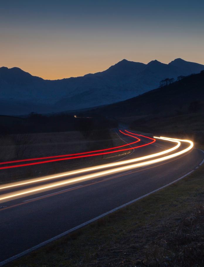 A4086 road with traffic trails at twilight and Snowdon Horseshoe in background