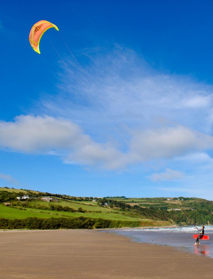 Kitesurfing holding a boar and a kite in Cardigan