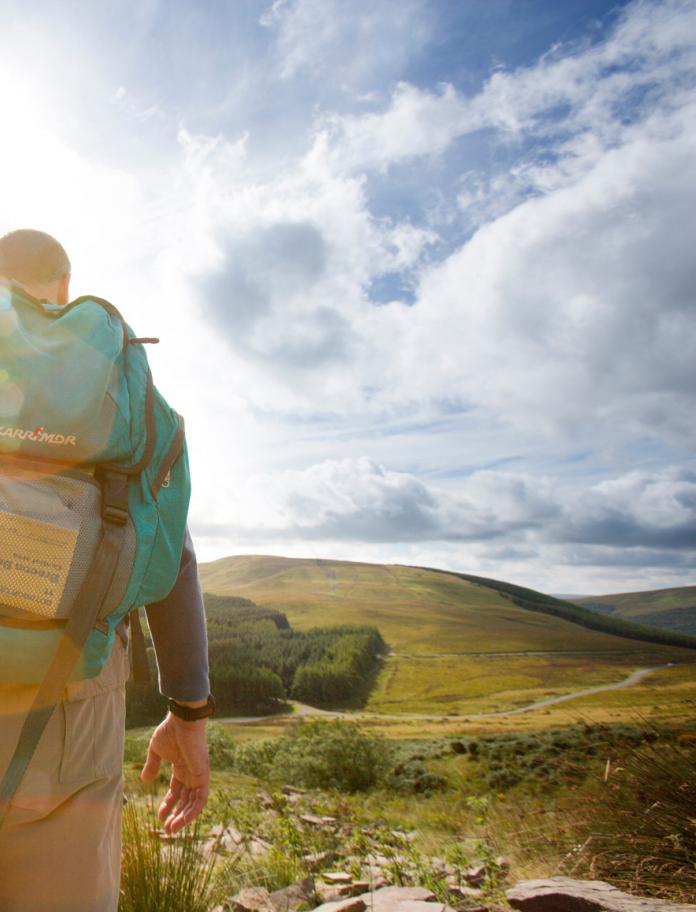 Photo of the back of a man with a rucksack hiking through the Brecon Beacons.