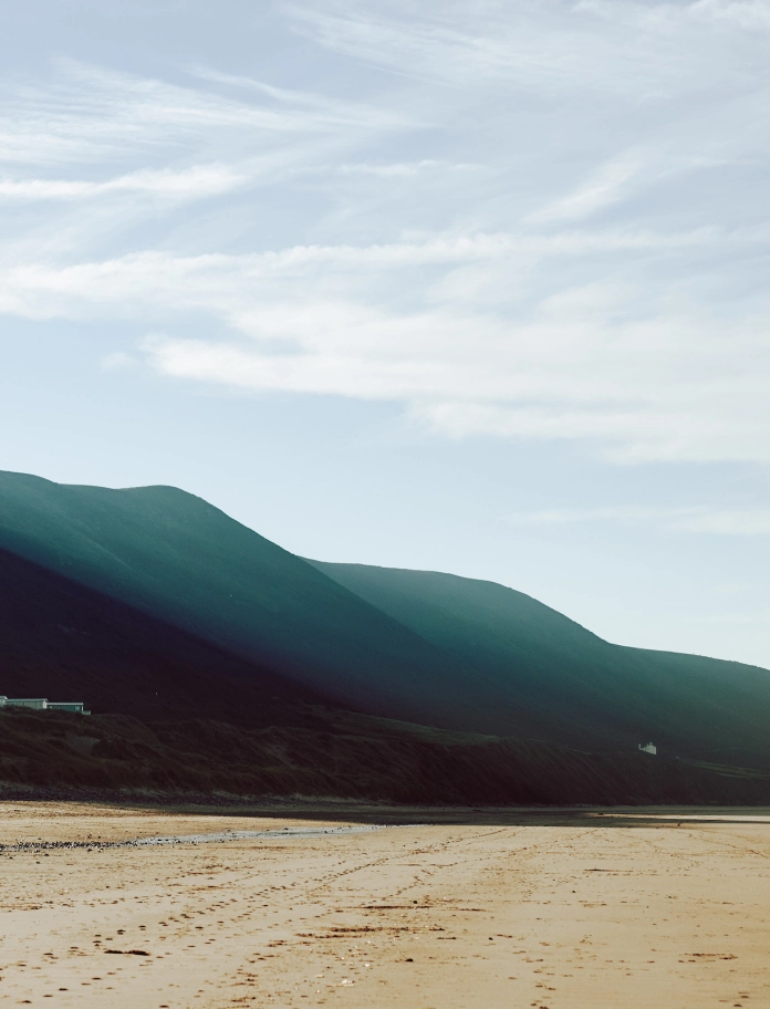 View of the sand on the beach with hills in the background 