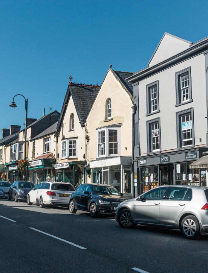 Photo of Cowbridge High Street taken from opposite side of the road with parked cars in shot.