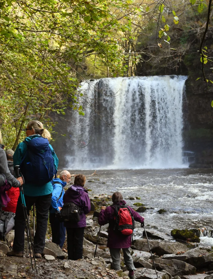 Group of walkers admiring Sgwd yr Eira waterfall