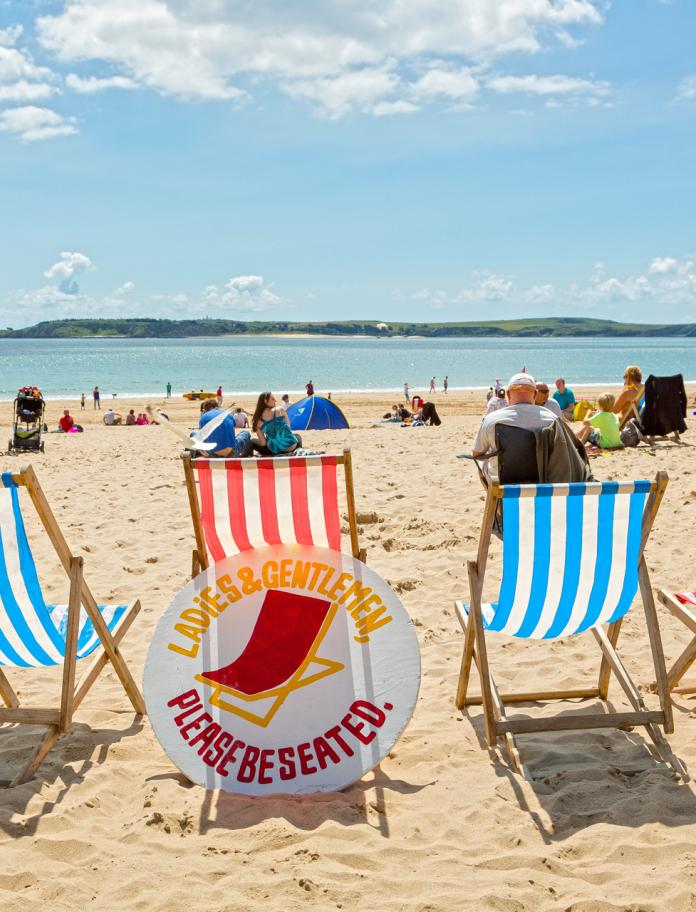 Castle Beach with deck chairs in foreground and Caldey Island in distance Tenby Pembrokeshire.
