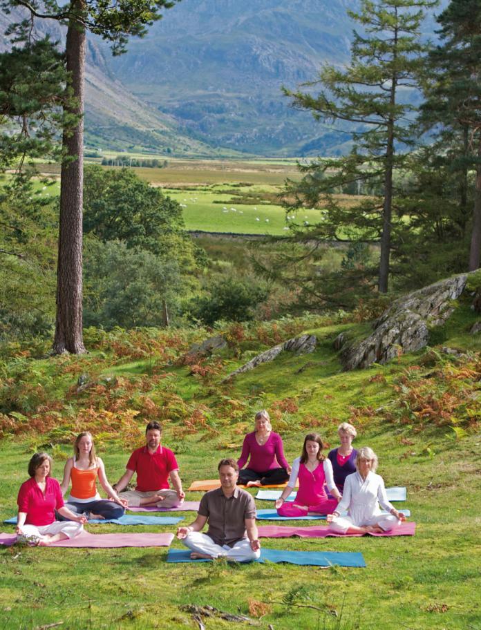 Group of people sitting and meditating by the Ogwen River, in Wales