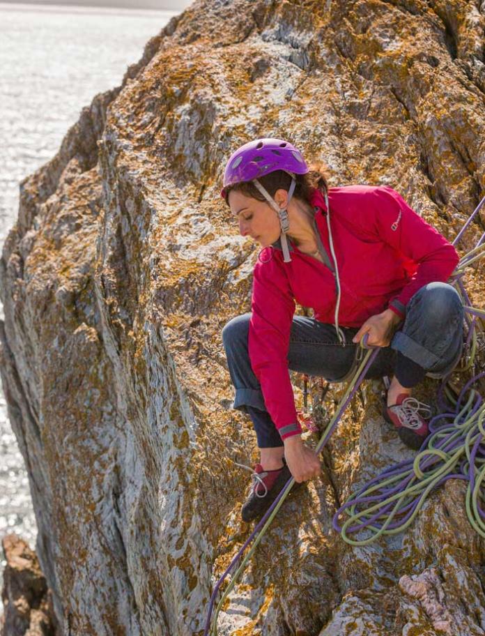 Female climber ascending sea cliff Rock Climbing Rhoscolyn Holy Island Anglesey