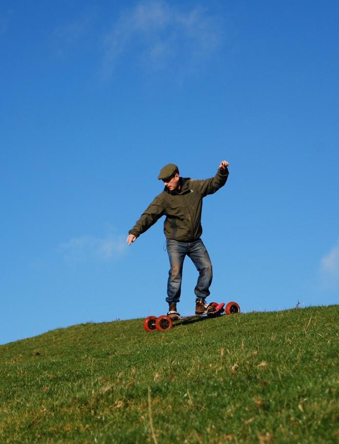 A man on a mountain board heading downhill.