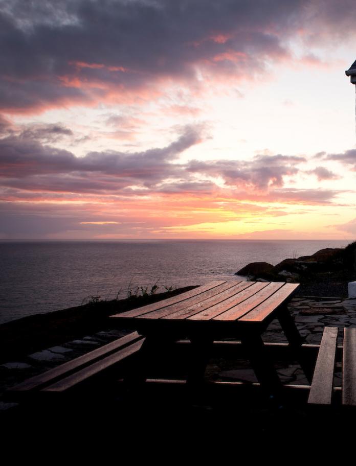 Outside of YHA Pwll Deri over looking the sea at sunset.