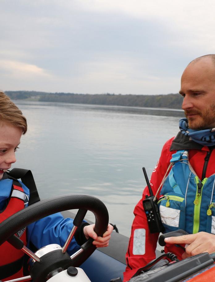 8 year old boy at the wheel of a speedboat.