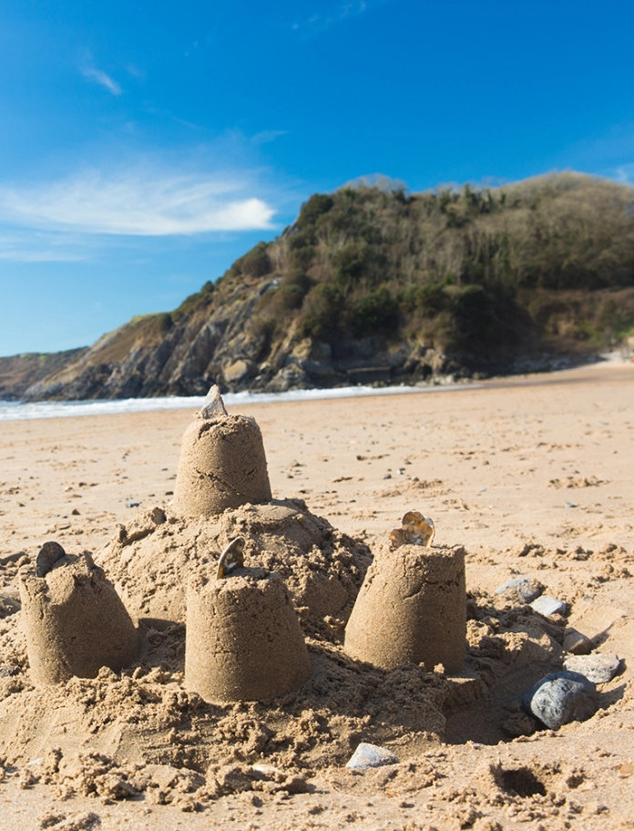 Sandcastles on the beach with the sea and sky in the distance.