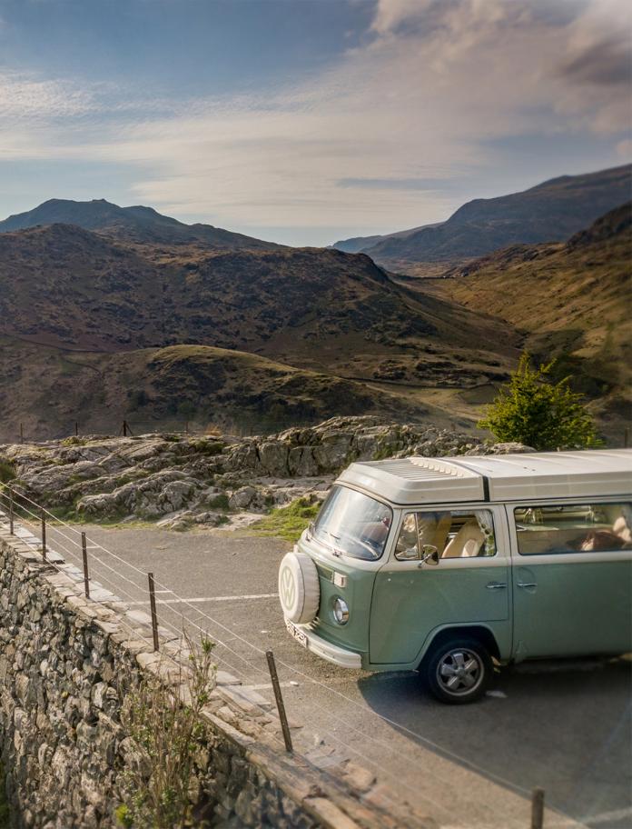 classic campervan parked with views of mountain with sunrays