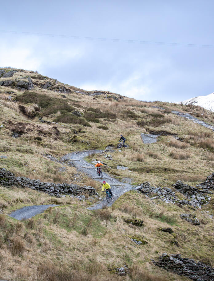 Two mountain bikers going down a bendy trail at Antur Stiniog.
