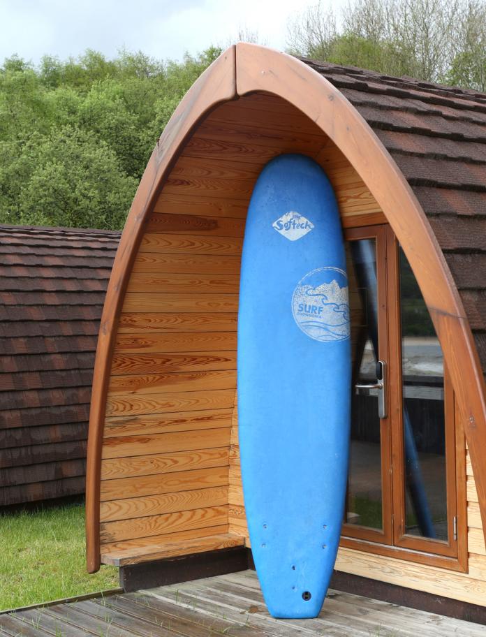 Glamping pod with a surfboard outside.