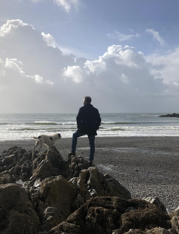 Image of a man and a dog looking out over Pwll Du Bay.