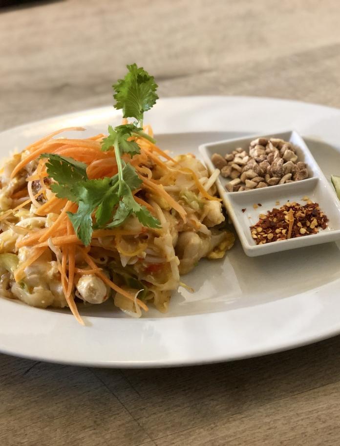 Ein Teller mit einem Thai-Gericht mit Cashewnüssen und Chilliflocken an der Seite.