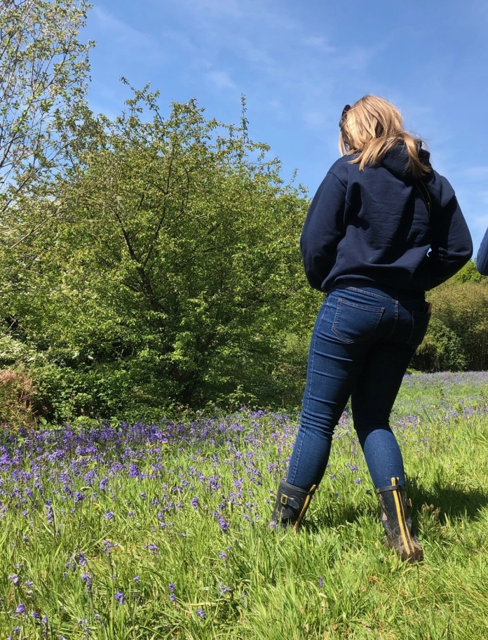Female and male walkers in field with bluebells.